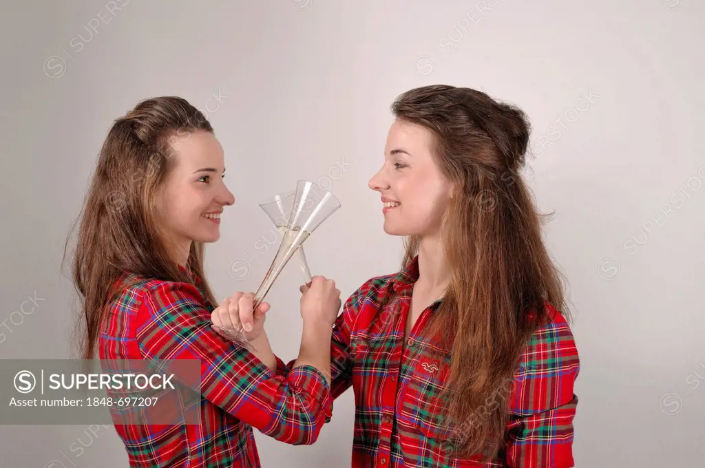 Twin sisters drinking to brotherhood from champagne glasses