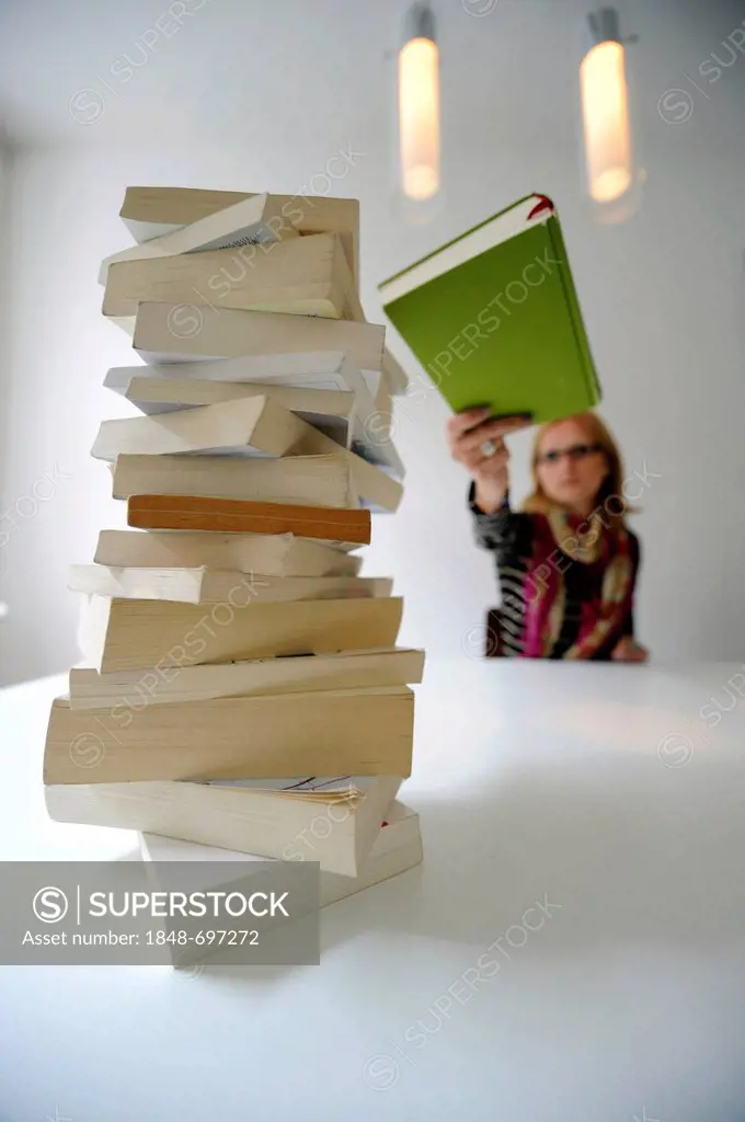 Stack of books in front of a woman holding a book