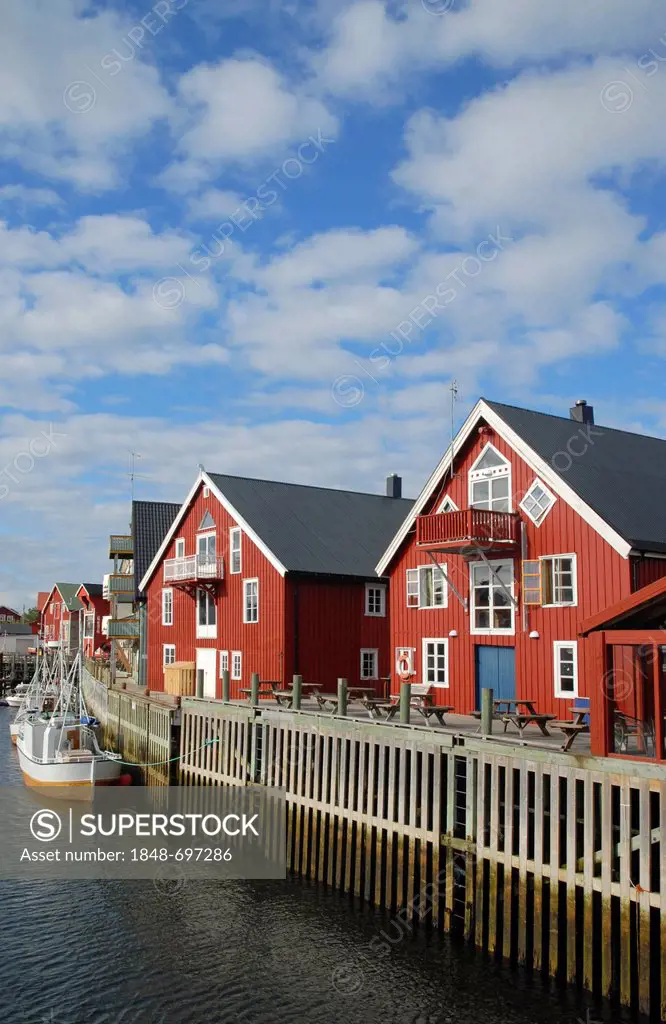 Typical red houses and fishing boats, blue sky and white clouds above, in Henningsvær, Lofoten, Nordland, Norway, Europe
