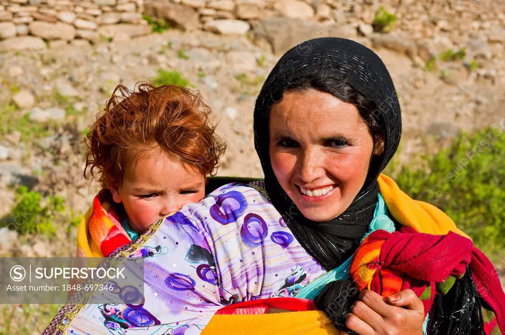 Woman, smiling friendly, carrying her baby in a sling on her back, High Atlas, Morocco, Africa