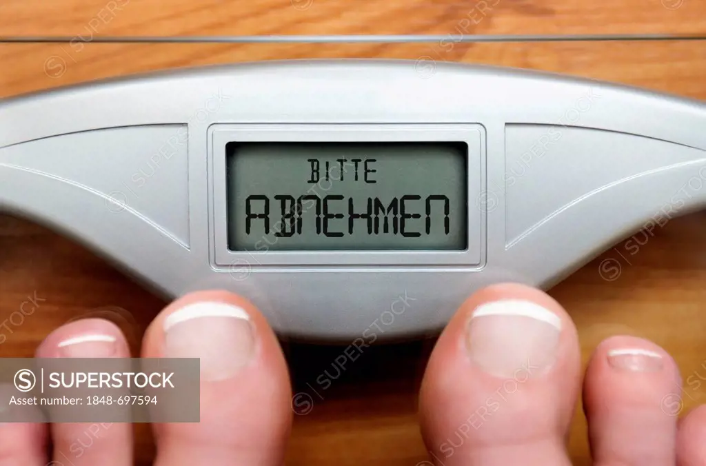Feet on scales with a digital display and the lettering Bitte abnehmen, German for please lose weight