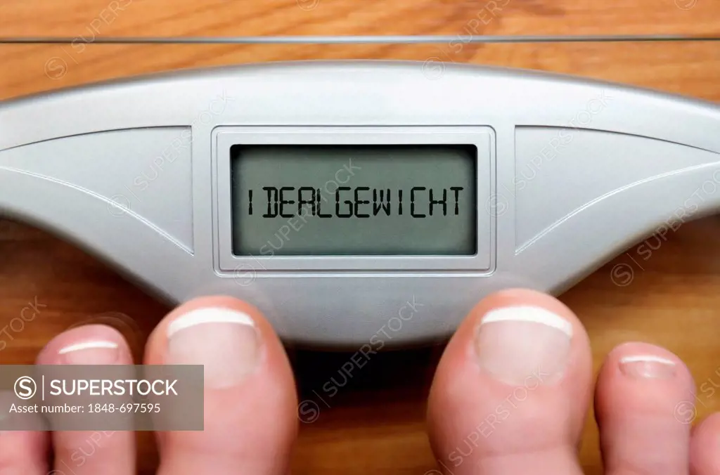 Feet on scales with a digital display and the lettering Idealgewicht, German for ideal weight