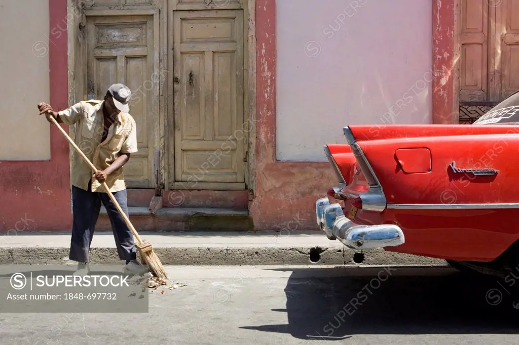 Road sweeper and classic american car in the old town, Santiago de Cuba, Cuba