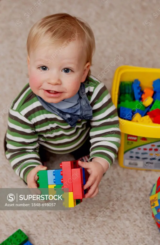 Young boy, 14 months, playing with colourful plastic Lego Duplo bricks, Germany