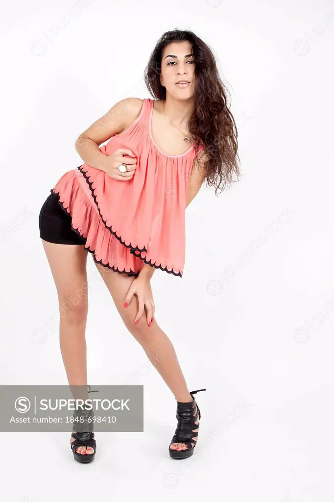 Young woman posing in a pink top, black hot pants and high heels
