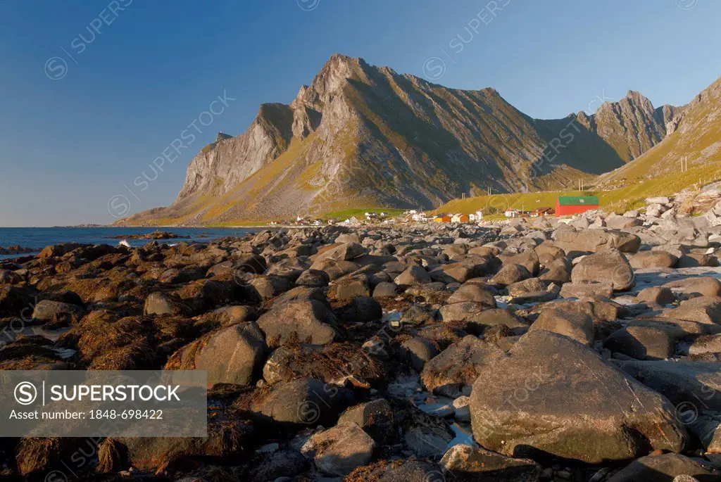 Mountains behind rocks on the beach of the Norwegian Sea, Vikten, Fredvang, island of Flakstadøya, Flakstadoya, Lofoten archipelago, Nordland, Norway,...