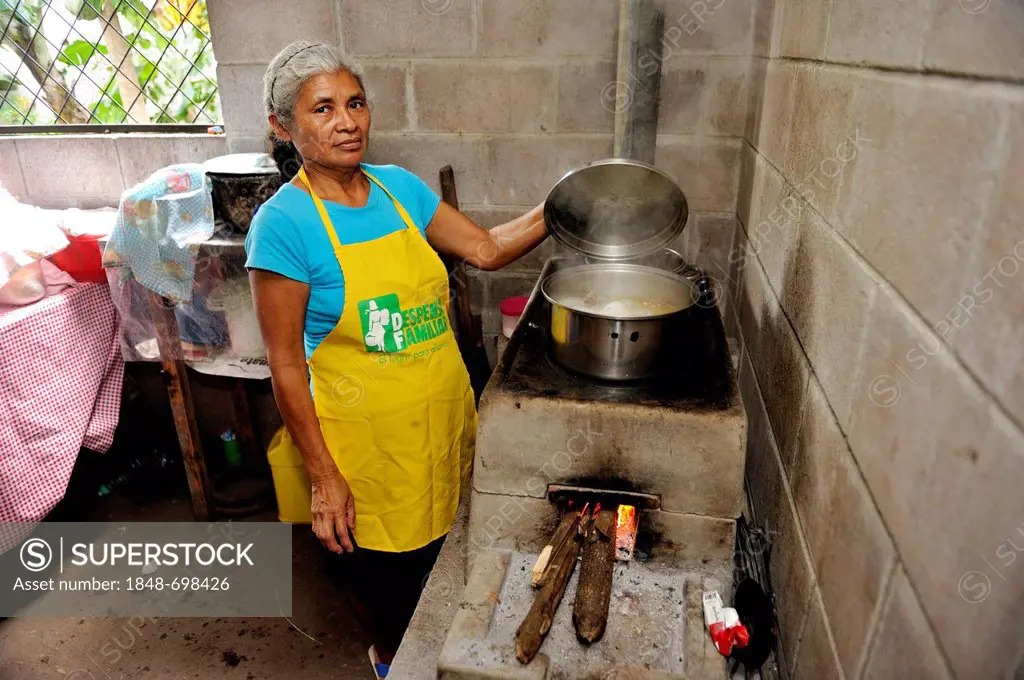 Female cook lifting the lid of a pot, cooking on an energy-saving stove, community of Cerro Verde, El Salvador, Central America, Latin America