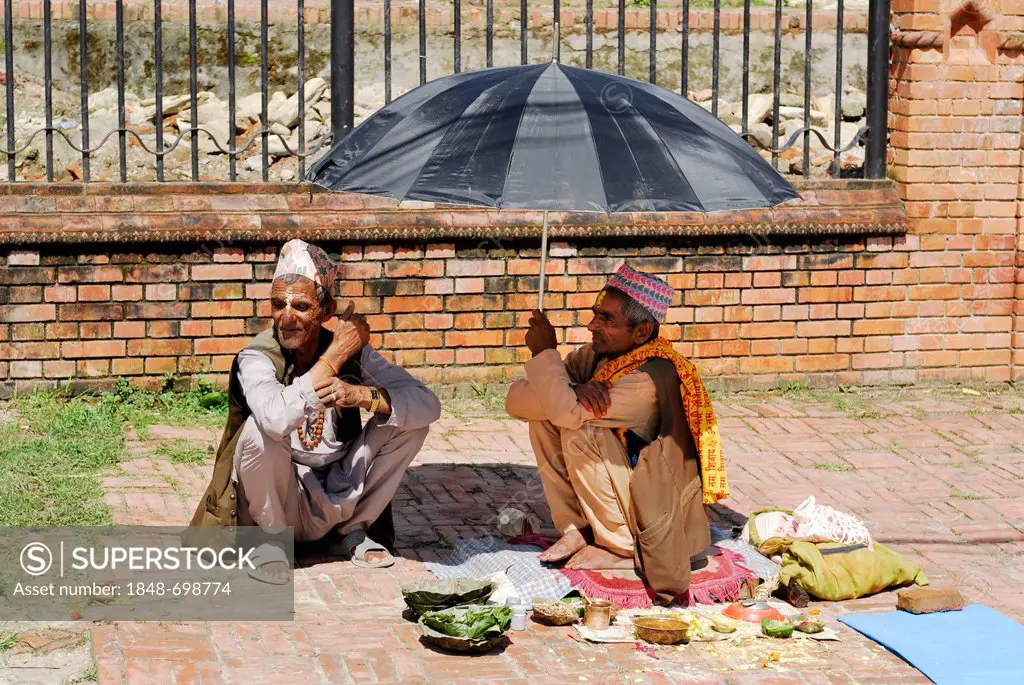 Men sitting under an umbrella, Kathmandu, Nepal, Asia