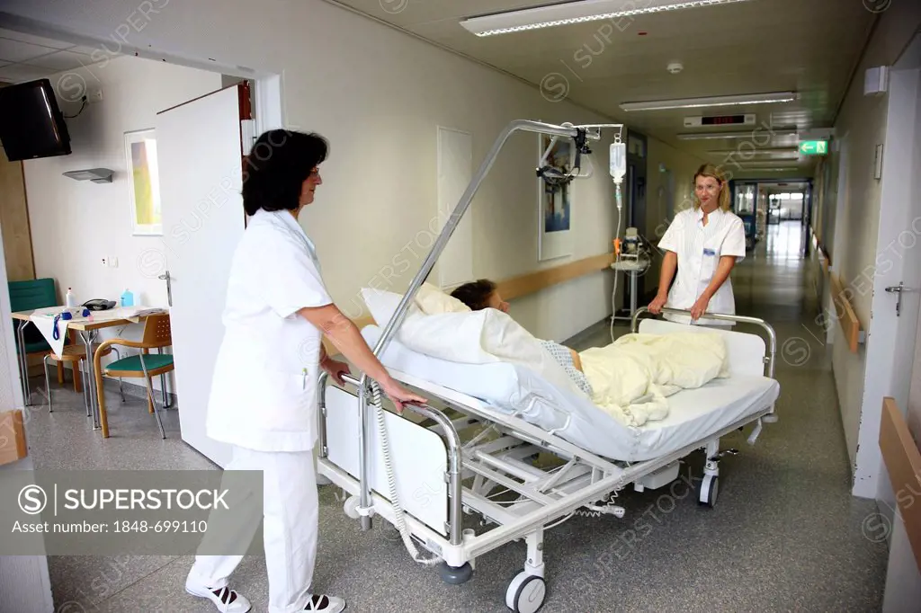Nurses transporting a patient in a bed within the station of a hospital