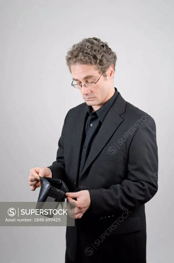 Businessman wearing a black suit looking at his empty wallet