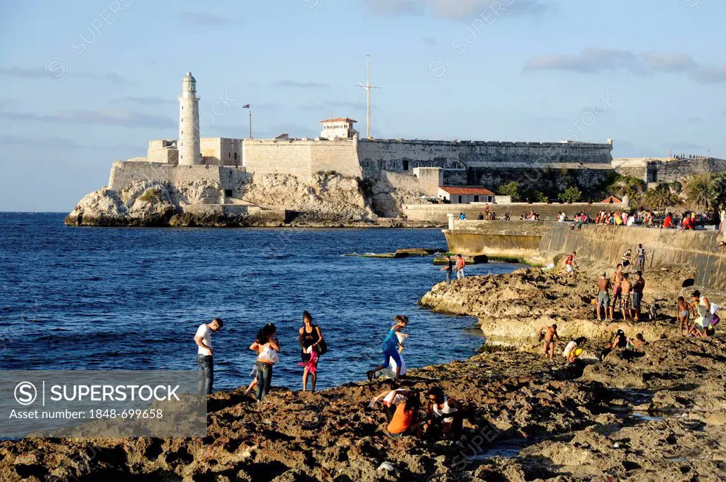 On the Malecon sea wall, Avenida de Antonio Maceo, a boulevard along the city centre of Havana, Centro Habana, with a lighthouse and a fort at the har...