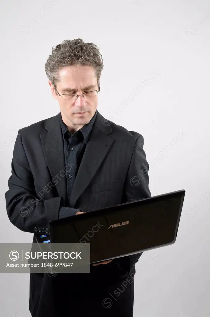 Businessman wearing a black suit holding a laptop