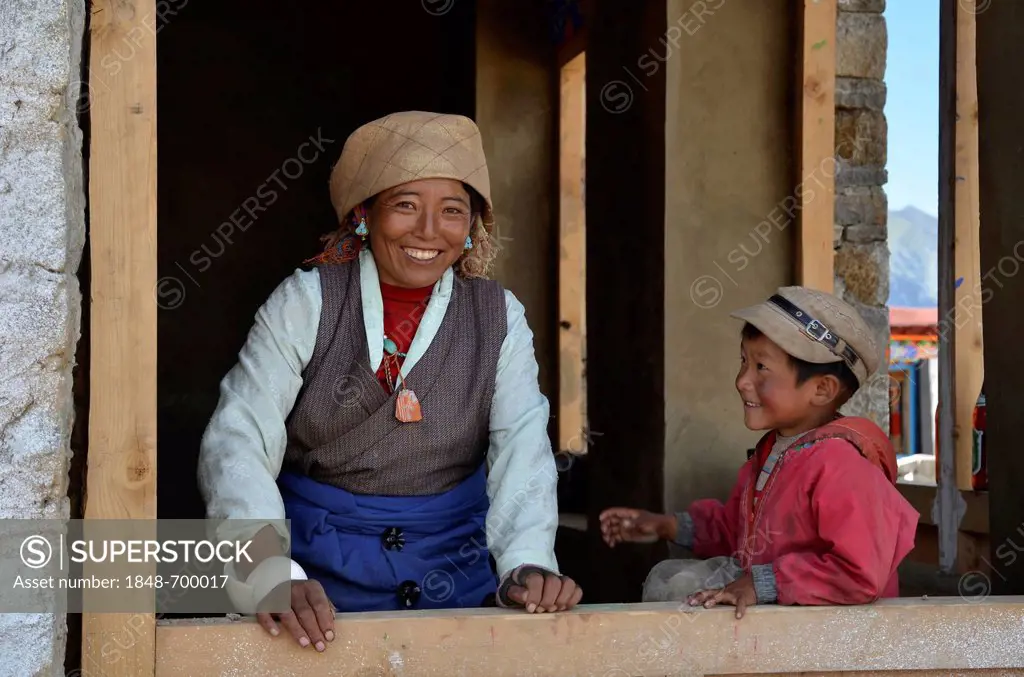 Tibetan woman with a child during the construction of a traditional Tibetan building, Pundo, Reting, Himalayas, Lhundrup County, central Tibet, Tibet,...