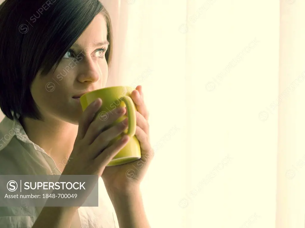 Young woman drinking coffee at a window