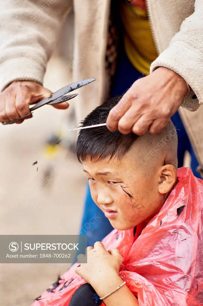 Palong boy getting a haircut at the roadside in Norlae village, northern Thailand, Asia