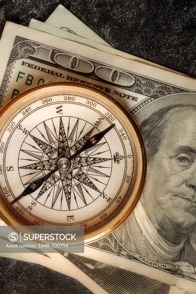 Antique gold compass on an array of US dollars, symbolic image for financial planning