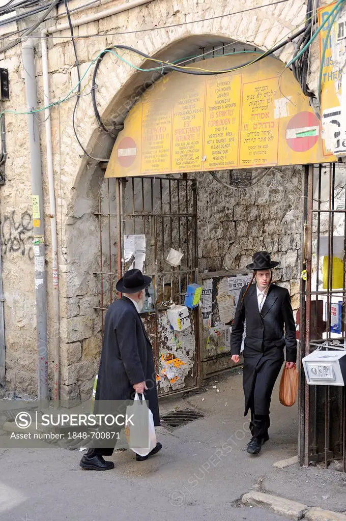 Sign prohibiting the entry of non-Orthodox Jews in a residential housing estate, with two Orthodox Jews passing through the gateway, in the district o...