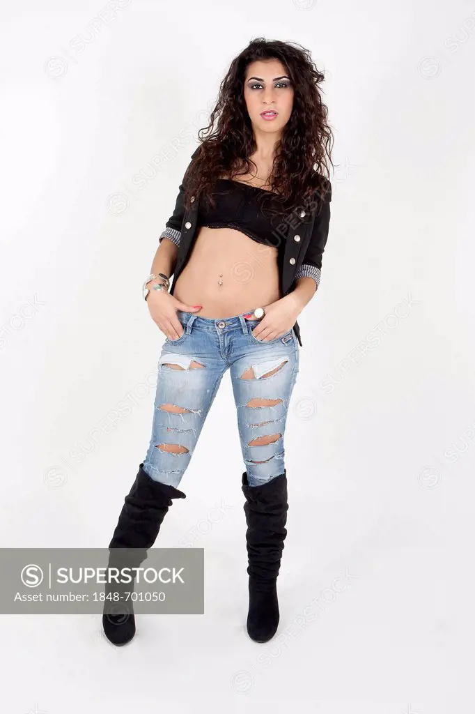 Young woman with a bare midriff, wearing a short jacket, jeans and boots
