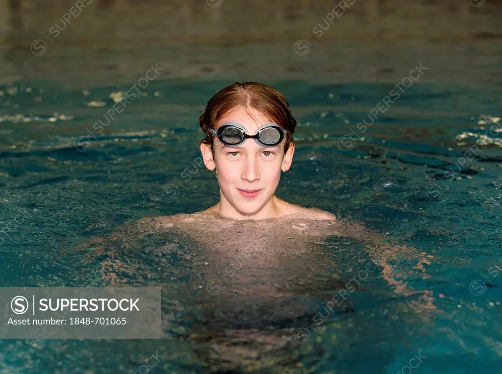 Boy, swimmer, 12 or 13 years, with swimming goggles in a swimming pool