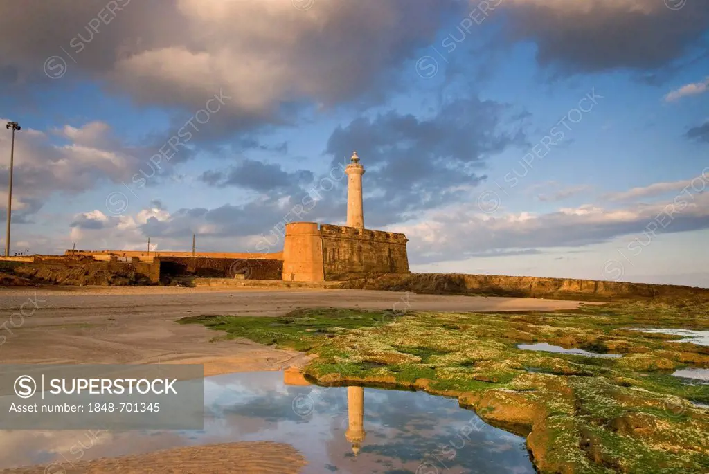 Clouds and blue sky above the lighthouse of Rabat, Phare de Rabat, and its reflection in a calm tide pool, at the Atlantic Ocean, Morocco, Africa