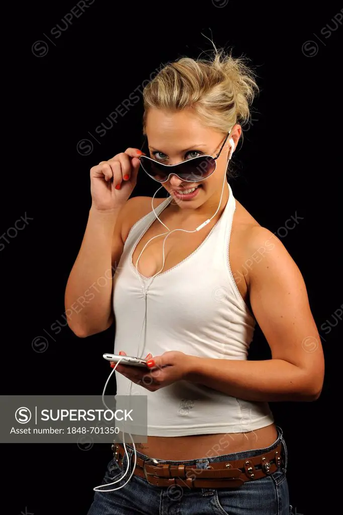 Young woman with sunglases operating a white Apple iPhone, listening to music, earphones, headphones