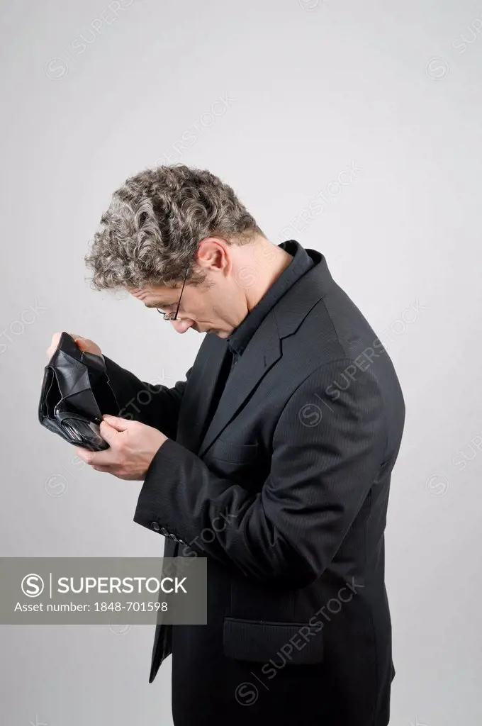 Businessman wearing a black suit looking into his empty wallet