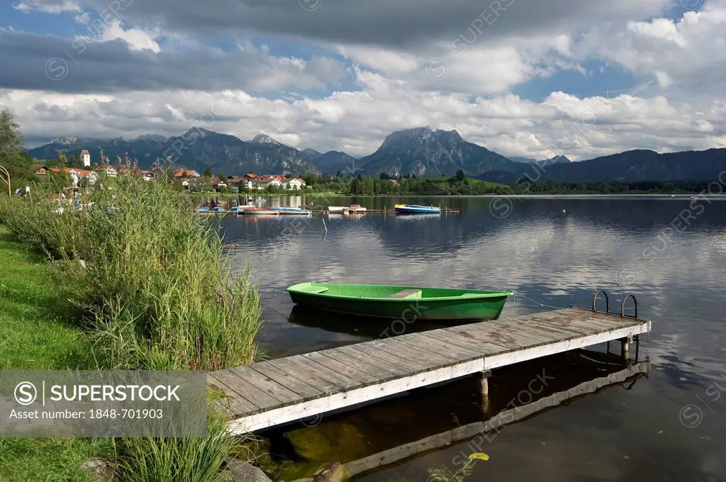 A wooden jetty and a boat on lake Hopfensee near Fuessen, Allgaeu, Bavaria, Germany, Europe