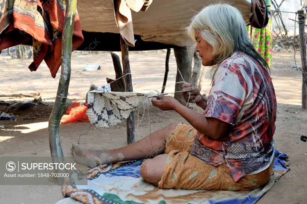 Indigenous woman, 71 years, from the Wichi Indians tribe, crafting a bag from the fibres of the Chaguar Bromeliad (Bromelia hieronymi), Comunida Santa...