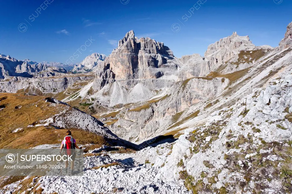 Mountaineer walking below Buellelejoch ridge, climbing Paternkofel mountain or Monte Paterno mountain, at the back, the peaks of Tre Cime di Lavaredo ...