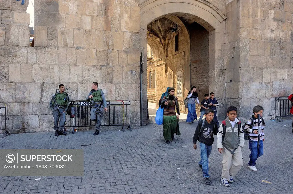 Israeli guards and Palestinian children with toy guns coming out from the Arab Quarter through the Lion Gate into the Old City of Jerusalem, Israel, M...