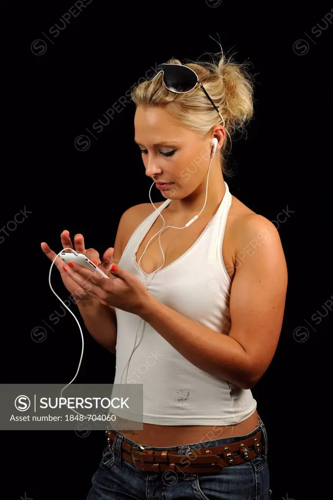 Young woman operating a white Apple iPhone, listening to music, earphones, headphones
