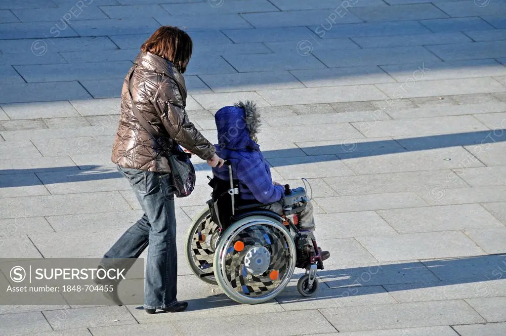 Woman sitting in a wheelchair being pushed, PublicGround