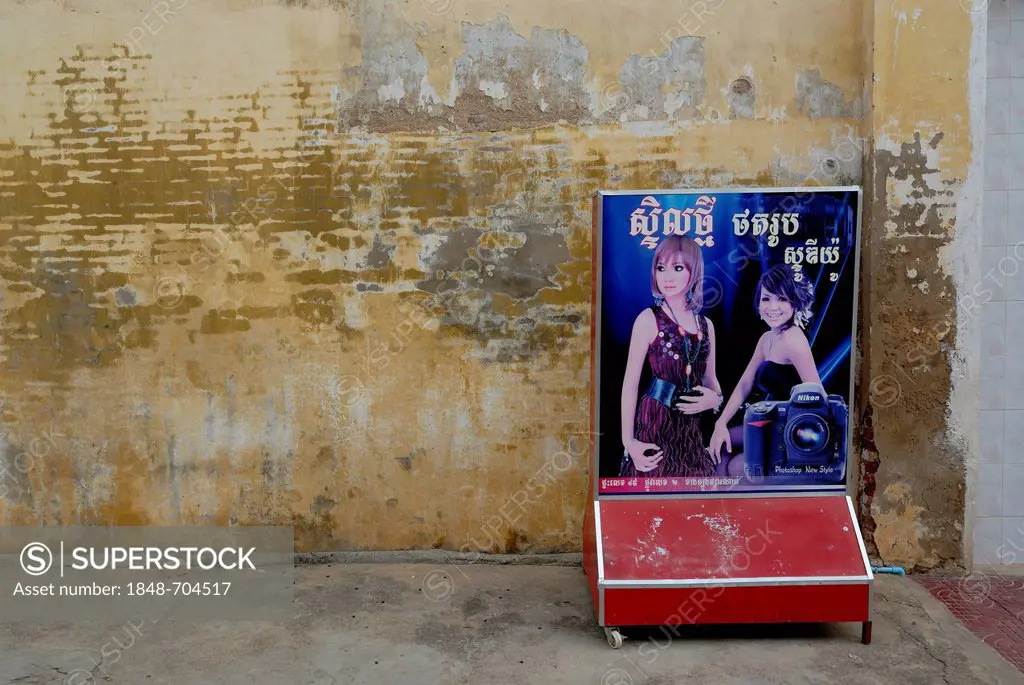 Cambodian advertising sign for Nikon cameras with Asian models in front of a damp wall, Battambang, Cambodia, Southeast Asia, Asia