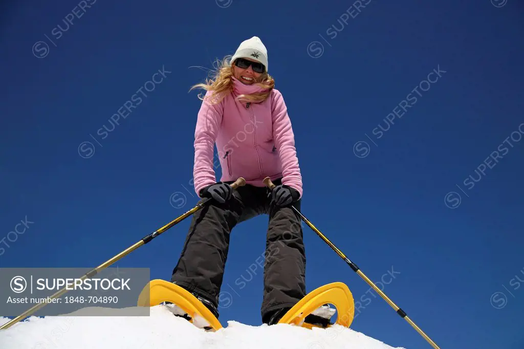 Young woman, about 25 years, snow shoe walking with sticks, against a blue sky, Thuringian Forest mountains, Thuringia, Germany, Europe