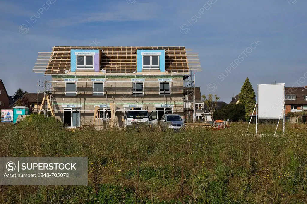 Building area, multi-family house surrounded by scaffolding with rafters, shortly before roof is being tiled, private residential building, PublicGrou...
