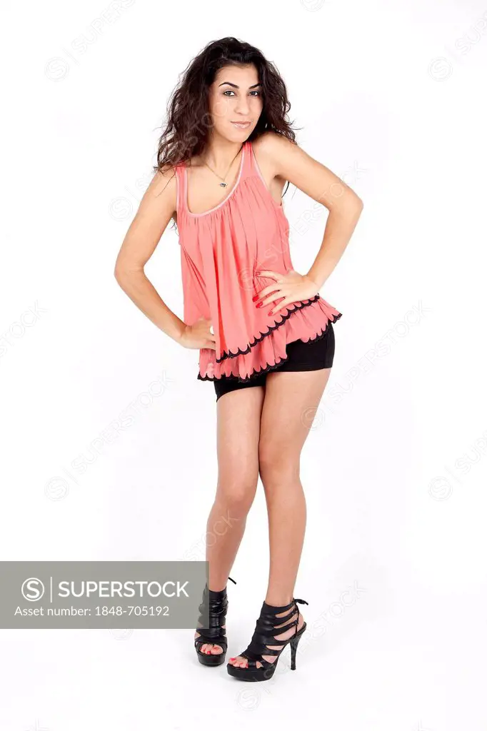 Young woman posing in a pink top, black hot pants and high heels
