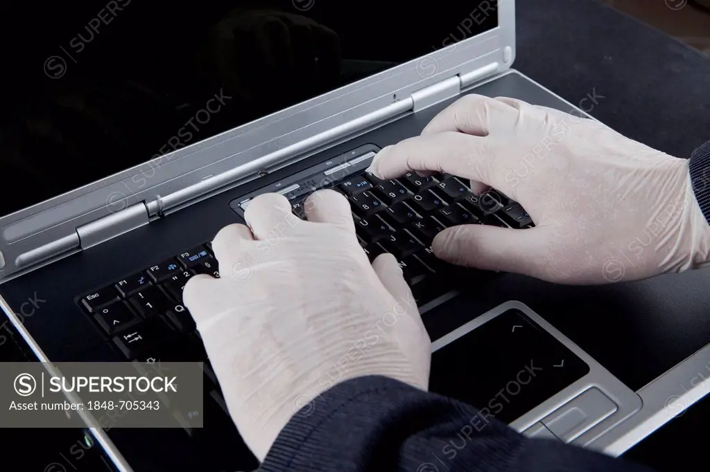 Hacker using a laptop, wearing latex gloves to leave no traces, symbolic image for Internet crime