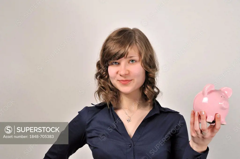 Young woman, 20, holding a pink piggy bank