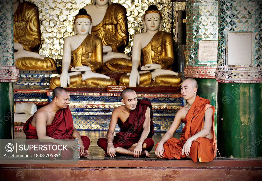 Buddhist monks sitting in front of Buddha statues in the Shwedagon Pagoda, Yangon, Burma also known as Myanmar, Southeast Asia, Asia