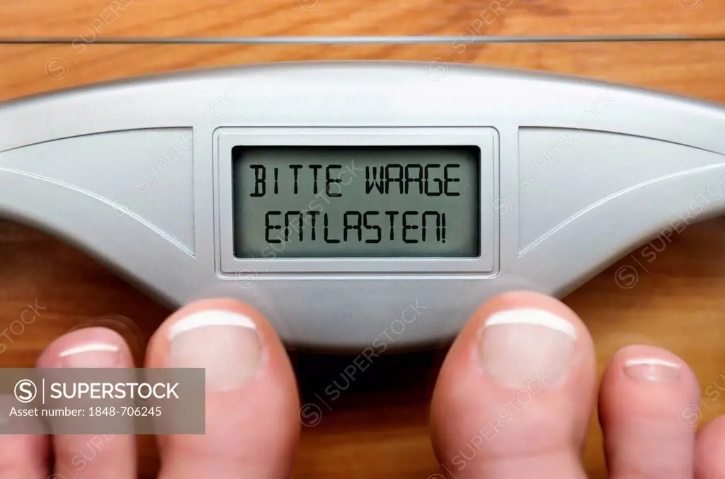 Feet on scales with a digital display and the lettering Bitte Waage entlasten, German for please unload scales