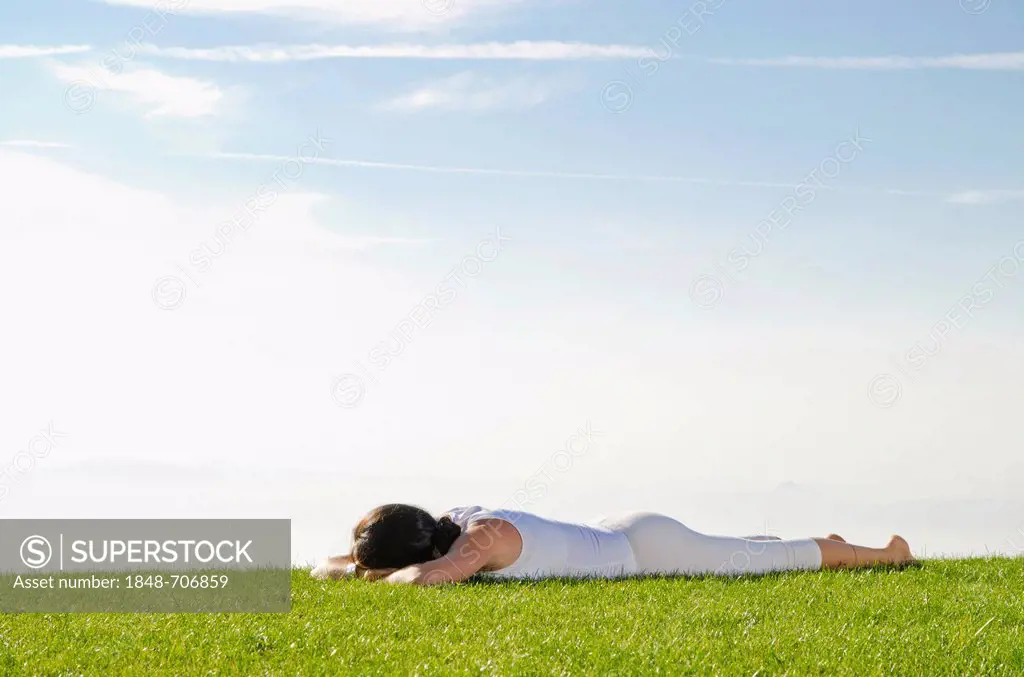 Young woman practising Hatha yoga outdoors, showing the pose advasana, reversed corpse pose, Nove Mesto, Okres Teplice, Czech Republic, Europe