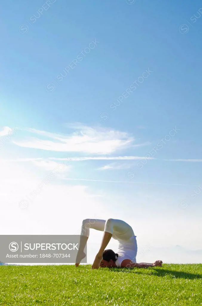 Young woman practising Hatha yoga outdoors, showing the pose poorna shalabhasana, full locust, Nove Mesto, Okres Teplice, Czech Republic, Europe