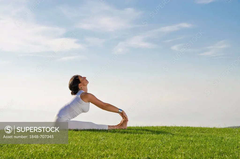 Young woman practising Hatha yoga outdoors, showing the pose pashchimottanasana, sitting forward bend, Nove Mesto, Okres Teplice, Czech Republic, Euro...