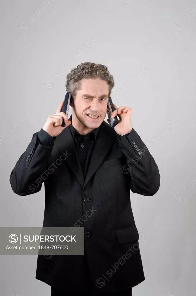 Businessman wearing a black suit talking on two mobile phones simultaneously