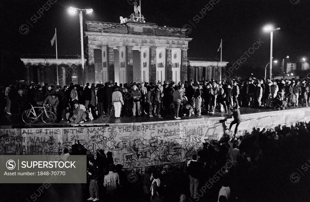 Fall of the Berlin Wall: people from East and West Berlin climbing the Wall at the Brandenburg Gate on the 9th November 1989, Berlin, Germany, Europe