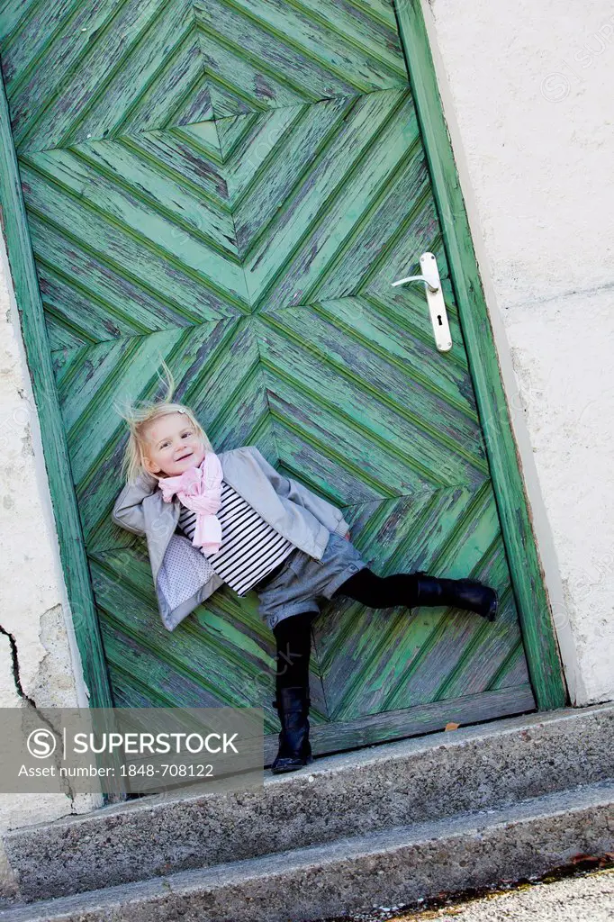 Girl, 2 years old, posing in front of a green door