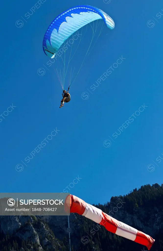 Paraglider, landing approach, upwind, a windsock in the foreground, Tegelberg mountain at back, Upper Bavaria, Germany, Europe, PublicGround