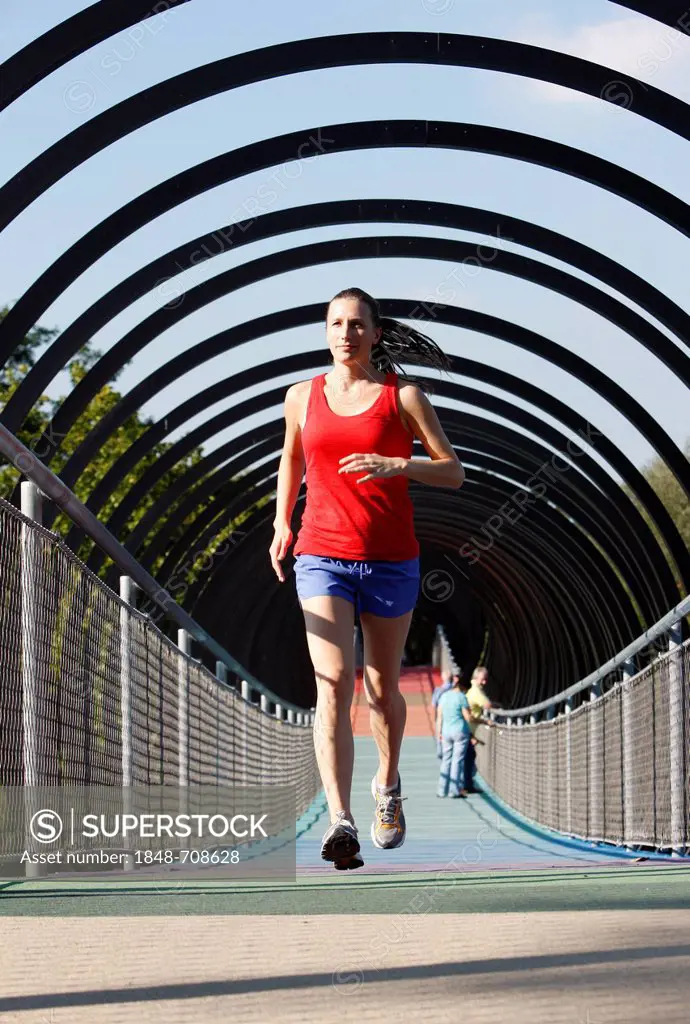 Jogger, runner, woman running on a pedestrian bridge, Slinky Springs to Fame, spiral-shaped bridge across the Rhine-Herne Canal near the Kaiserpark vi...