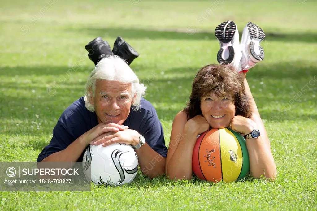 Smiling senior couple with two balls lying on lawn, Erfurt, Thuringia, Germany, Europe