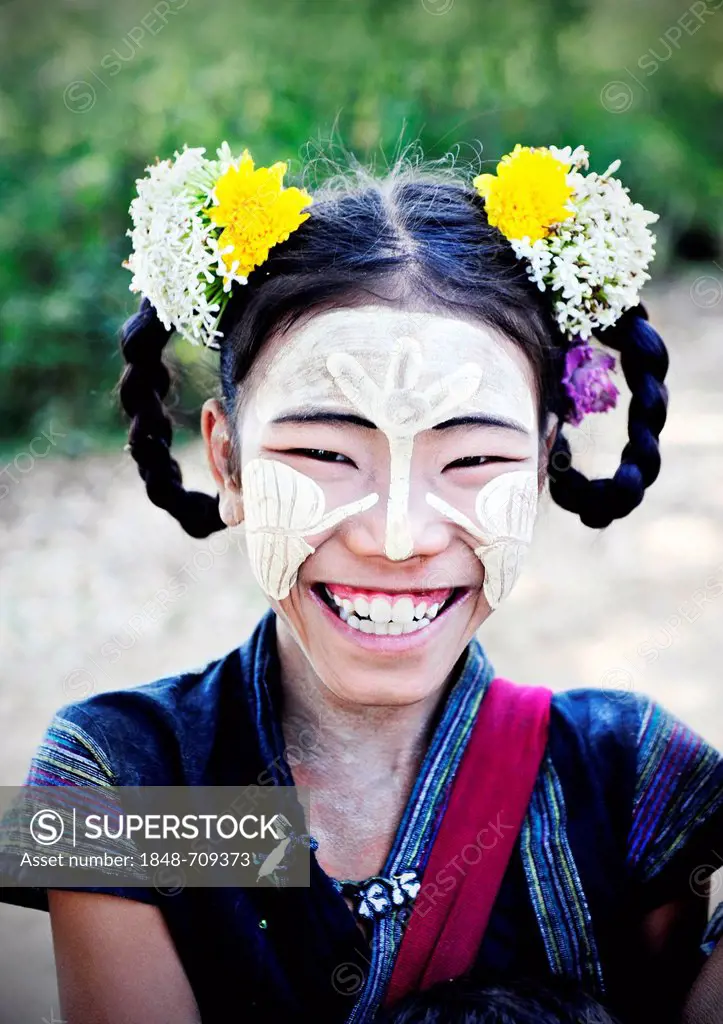 Smiling girl wearing thanaka paste on her face and flowers in her hair, Bagan, Myanmar, Burma, Southeast Asia, Asia